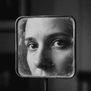 زنی که با نگرانی به افتادگی پلک خود در آینه نگاه می‌کند و به دنبال درمان است.